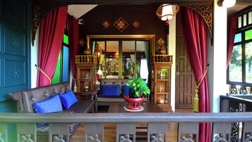 A room with a sofa, a table with a plant, and a decorative railing.