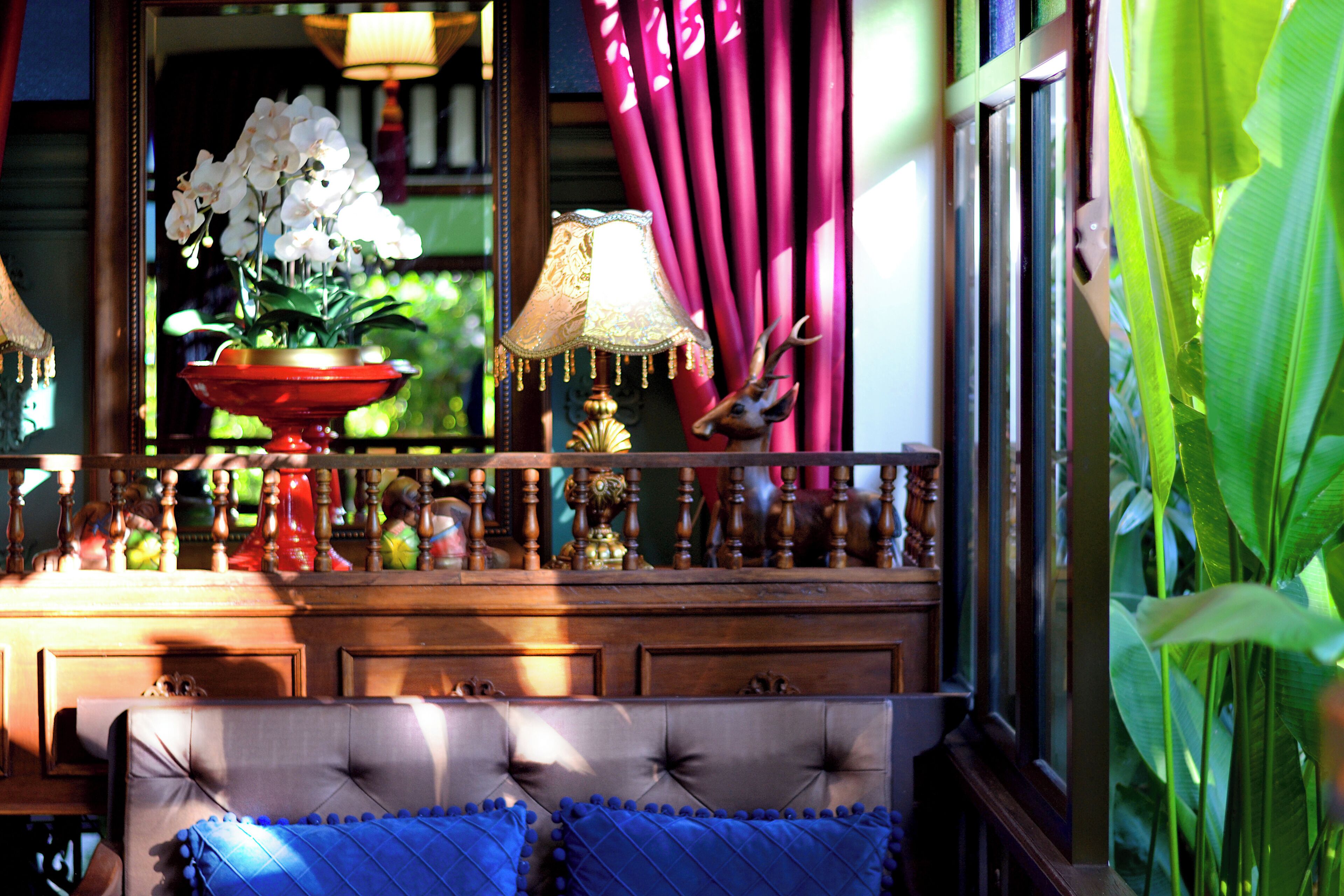 A room with a tufted headboard, a red bowl with white flowers, a lamp, and a deer figurine.