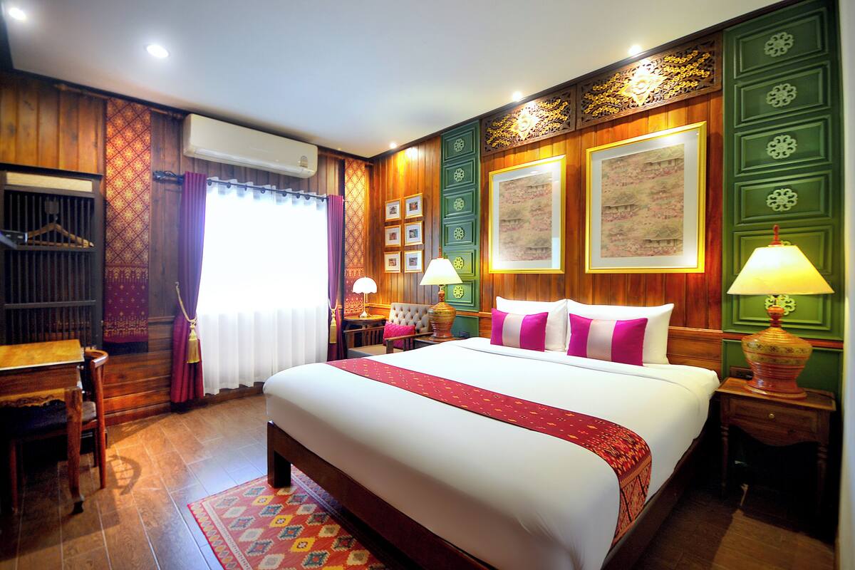 Een hotelkamer met een groot bed, houten lambrisering, een bureau en een stoel.