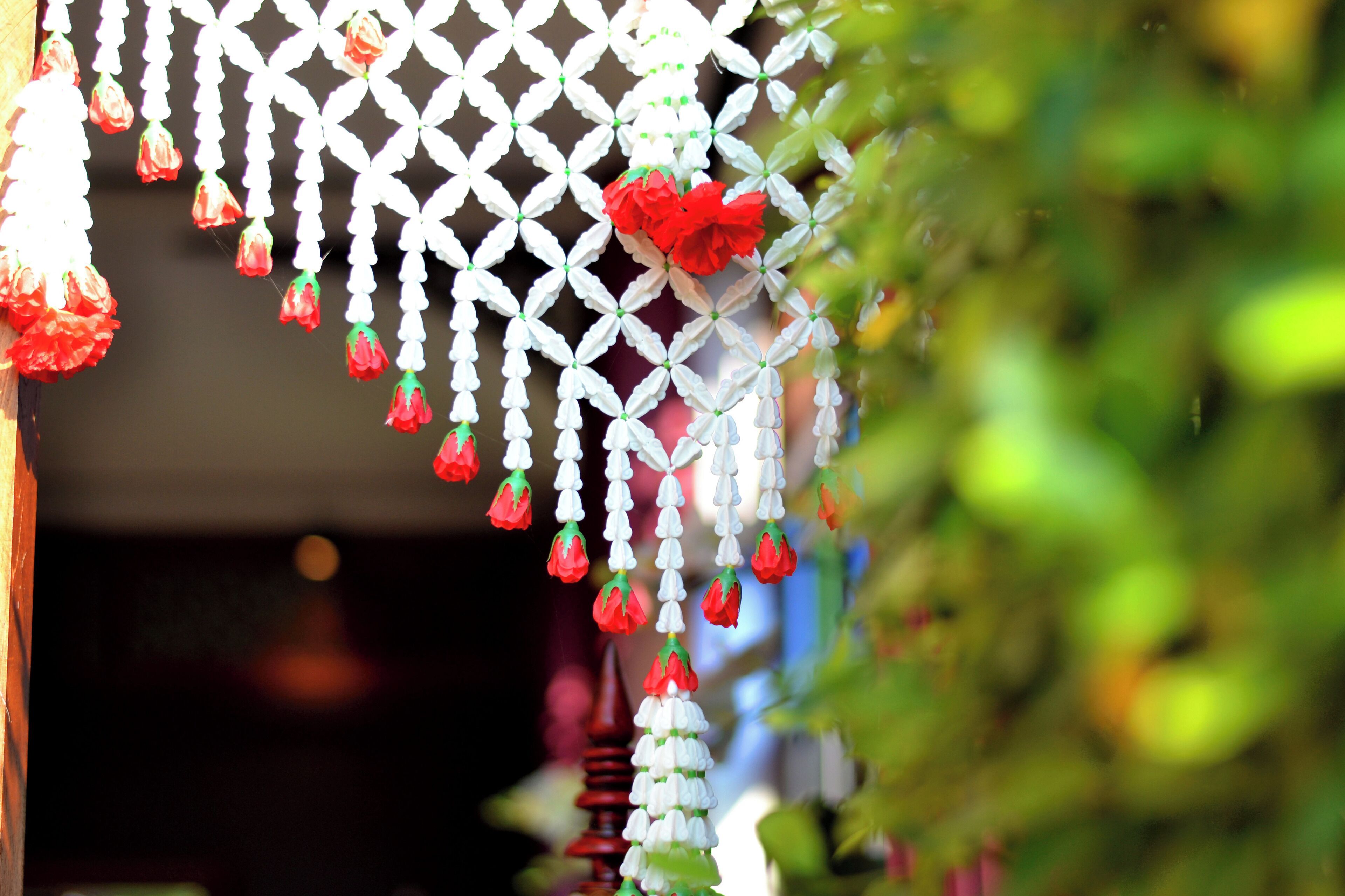 A decorative hanging with red flowers and white elements.