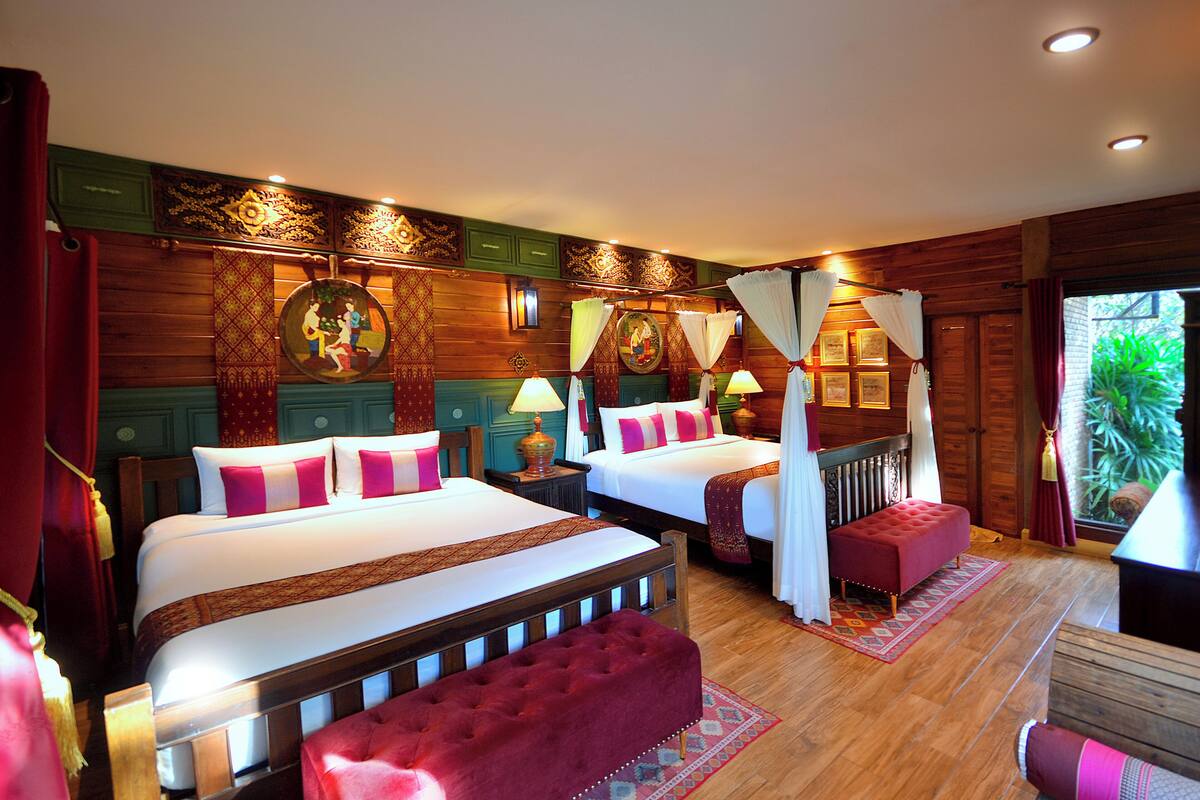 Een hotelkamer met twee bedden, een rode bank en uitzicht op groen.