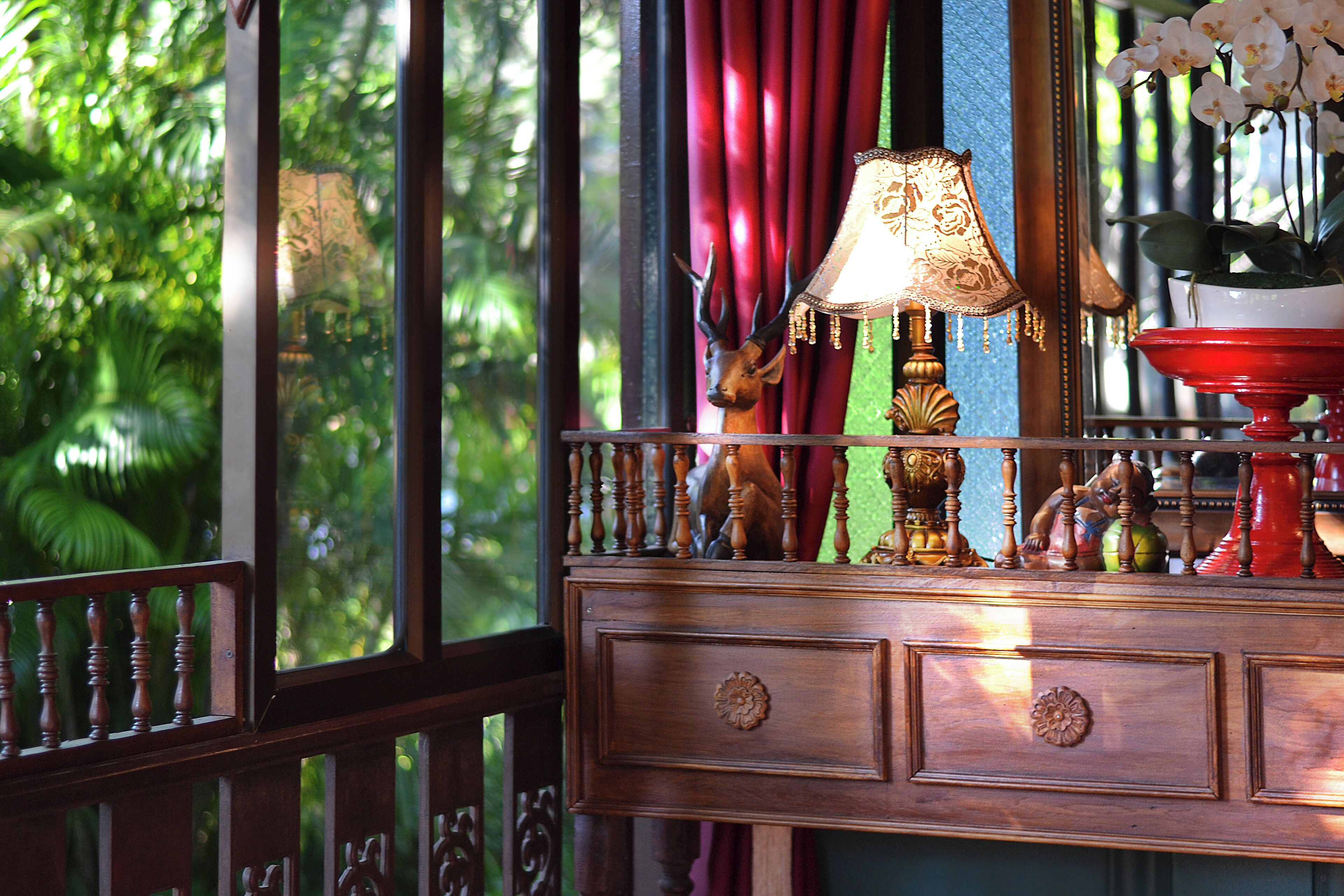 A wooden dresser with drawers, a lamp, and a decorative deer head.