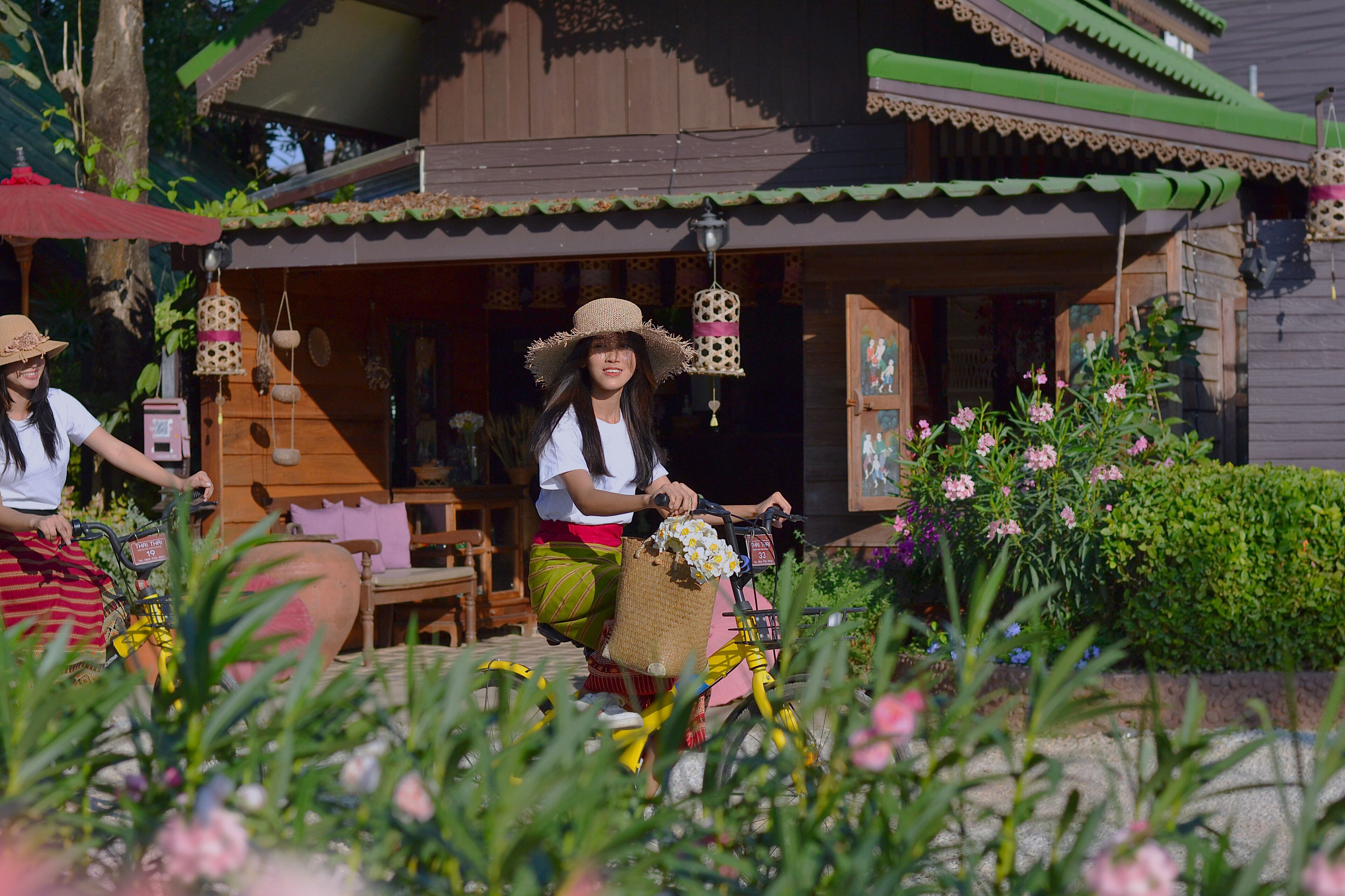 Une maison traditionnelle en bois avec un porche, un vélo avec un panier, et une personne qui fait du vélo.