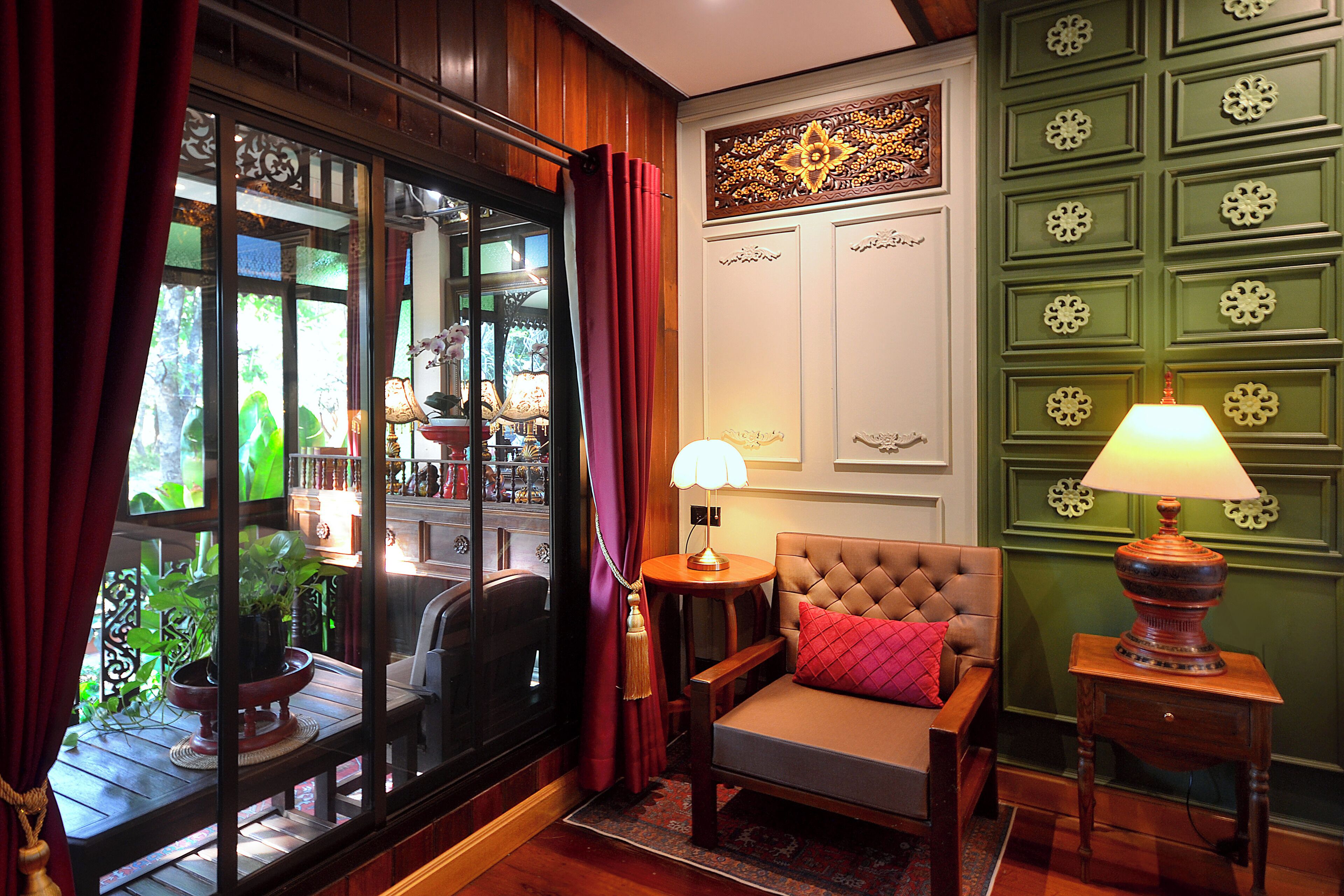 A cozy room with a large window, a comfortable sofa, a small table with a lamp, and a green wall with decorative panels.