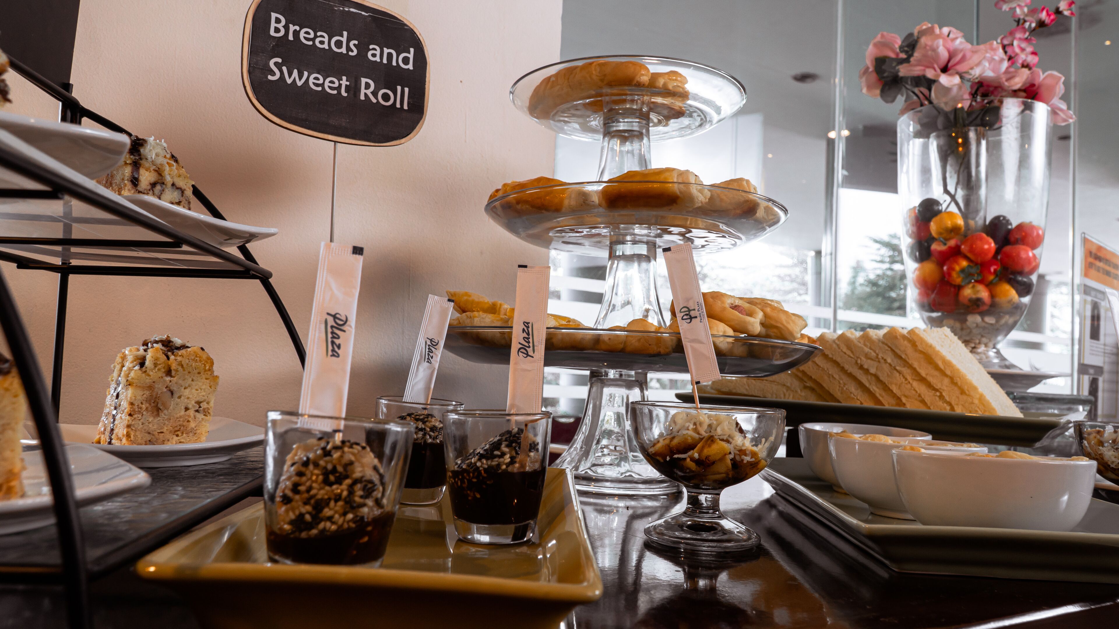 A bakery display with breads, sweet rolls, and pastries, along with a sign reading "Breads and Sweet Roll".
