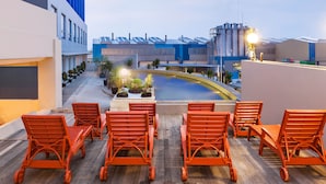 Una terrazza sul tetto con poltrone da relax arancioni, una piscina e moderni edifici sullo sfondo.