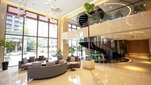 A modern lobby with a curved seating area, a spiral staircase, and large windows offering views of the street. - He Ti Hotel (Taichung)