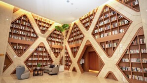 A library with bookshelves arranged in a unique geometric pattern, a comfortable seating area, and a polished marble floor. - He Ti Hotel (Taichung)