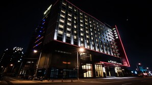 A modern hotel with a prominent red neon sign, multiple floors, and illuminated windows. - He Ti Hotel (Taichung)