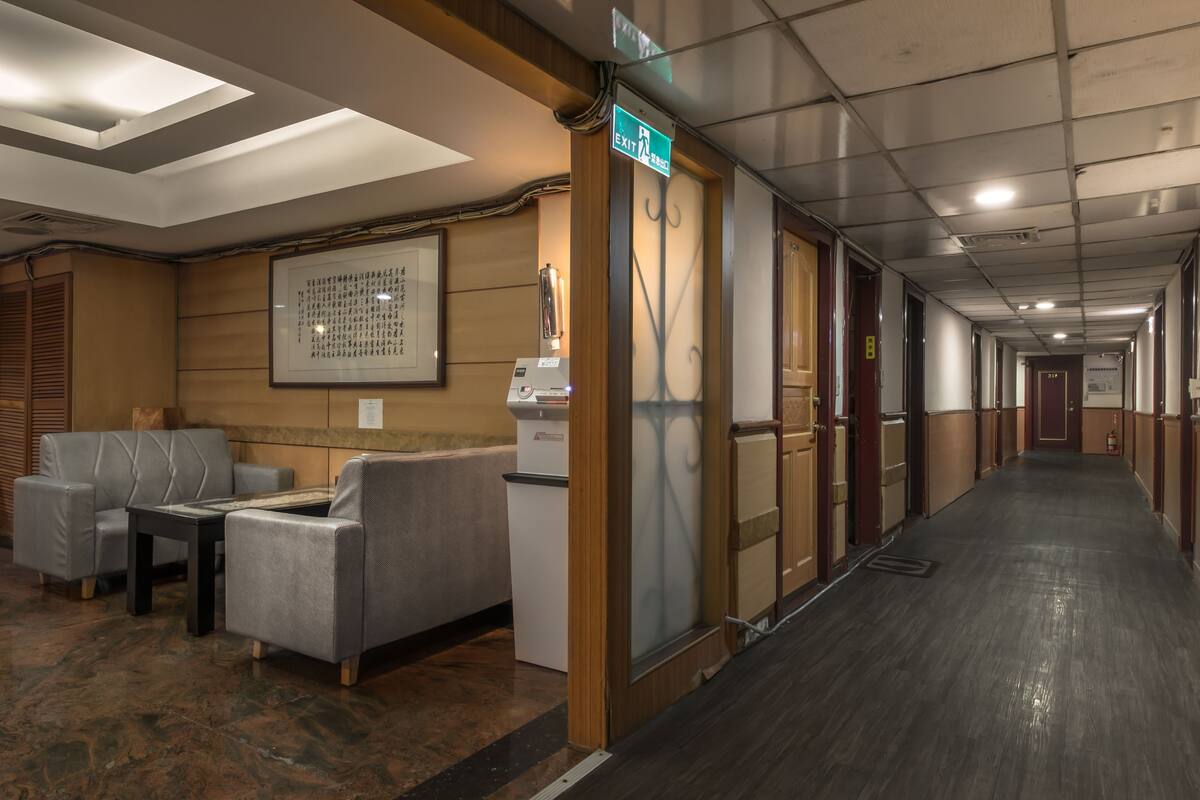 A hotel corridor with seating, a reception desk, and an exit sign.
