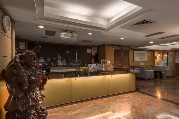 A reception area with a statue, a counter, and seating.