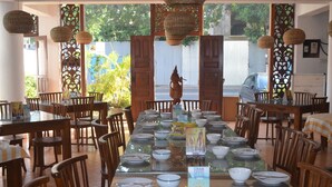 Un comedor con una mesa larga dispuesta para una comida, rodeado de sillas de madera.