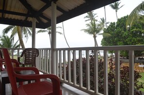 A covered outdoor seating area with red plastic chairs and a white railing. - Hotel Paradiso (Hikkaduwa)
