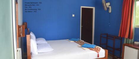 A DELUXE ROOM with a private bathroom, mosquito net, fan, air conditioning, and hot water.