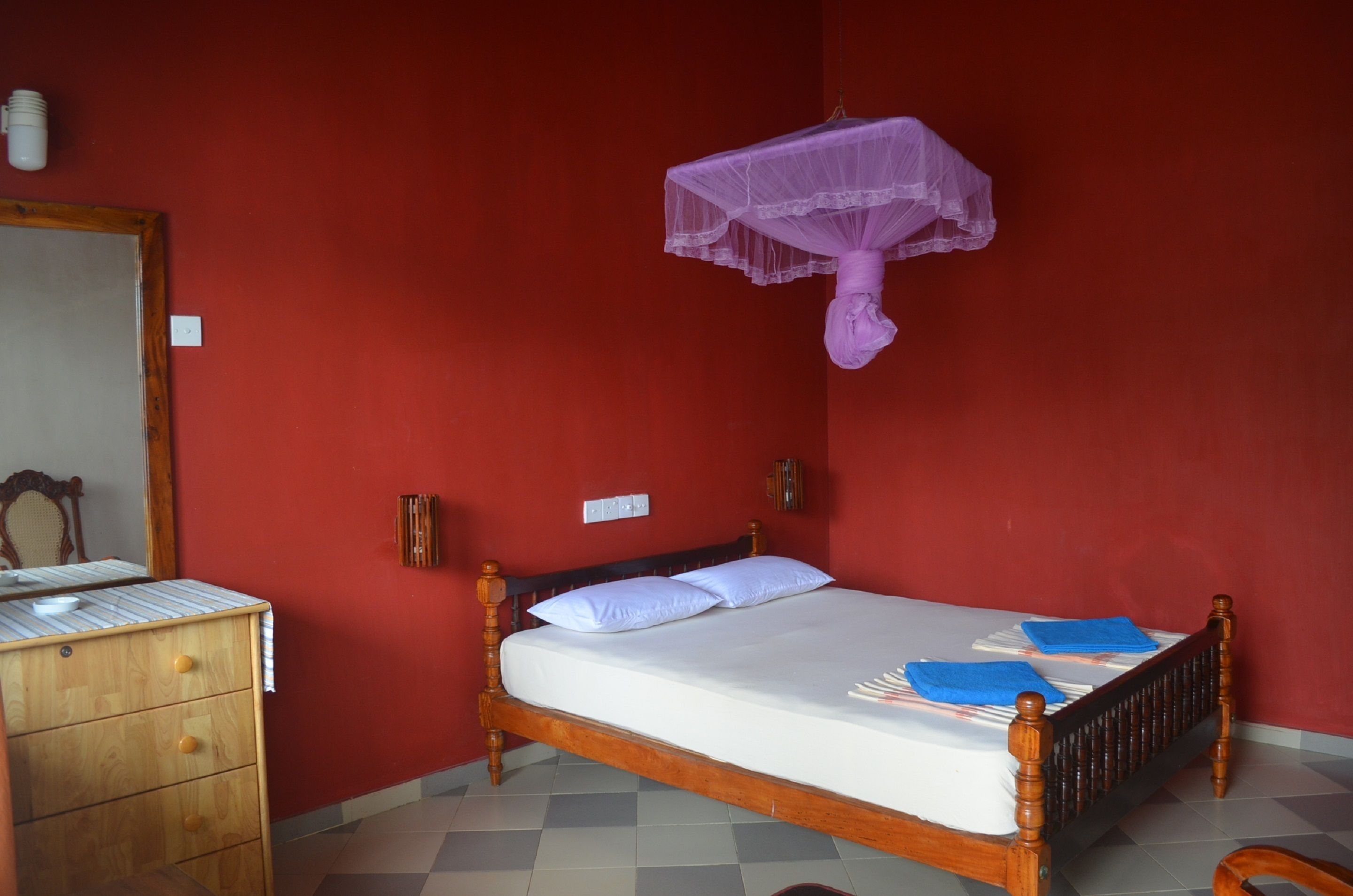 Ein Zimmer mit einem hölzernen Bett, einem Schminktisch und einem Spiegel.