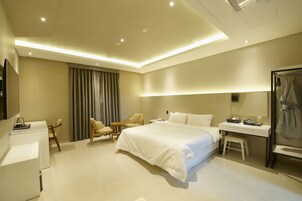 Una habitación de hotel moderna con una cama grande, un escritorio, una silla, un televisor y un baño.