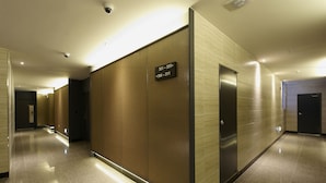 A modern hotel corridor with a sign indicating room numbers 301-305 and 306-311. - Hotel B (Gwangju)
