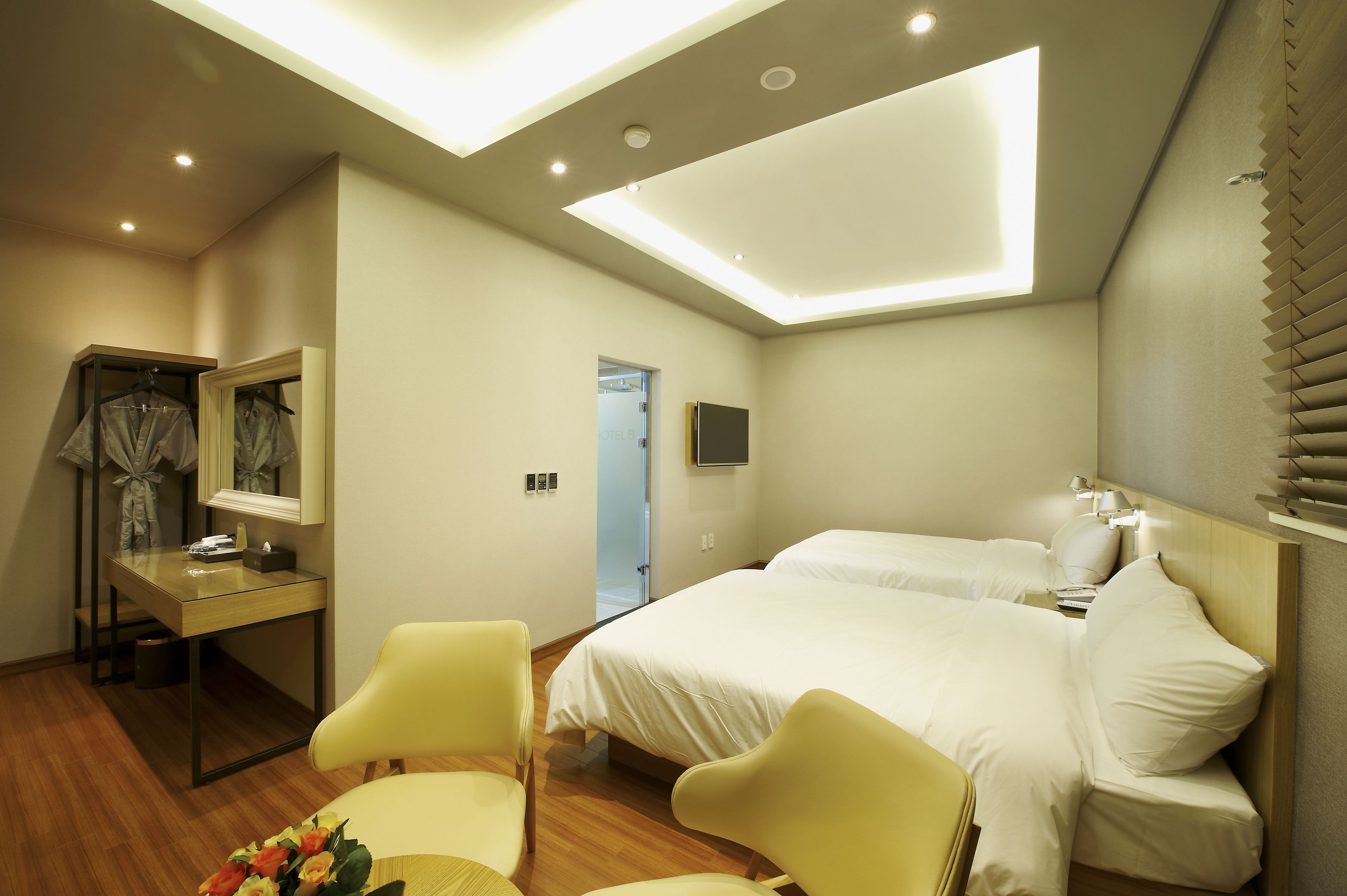 A hotel room with a bed, a desk, a chair, and a mirror.
