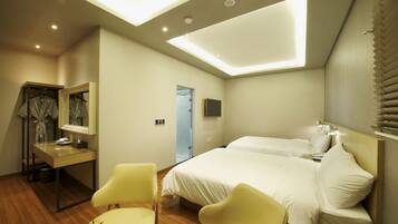 A hotel room with a bed, a desk, a chair, and a mirror.