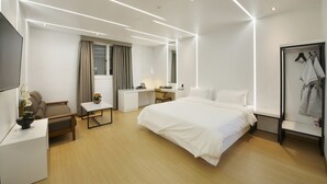 A modern hotel room with a large bed, a desk, a chair, a TV, and a wardrobe. - Hotel B (Gwangju)