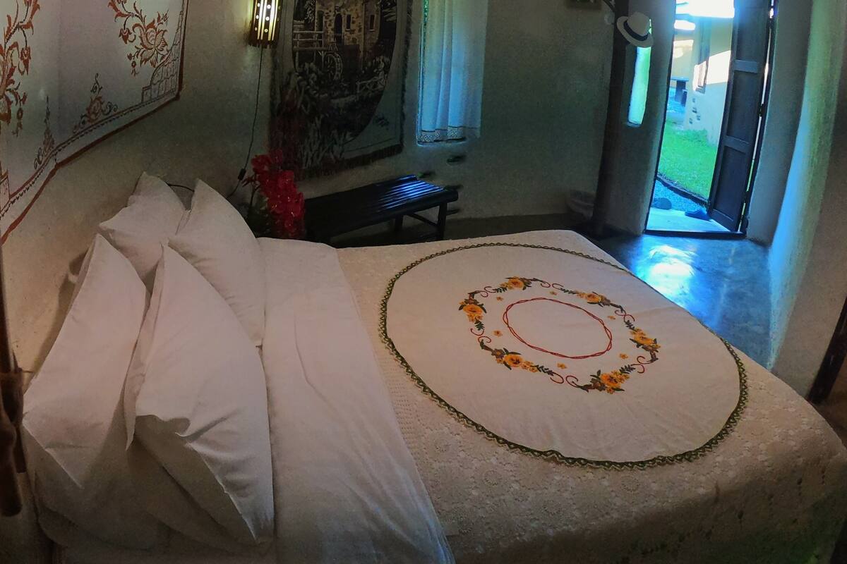 A bedroom with a bed, a bench, and a tapestry on the wall.