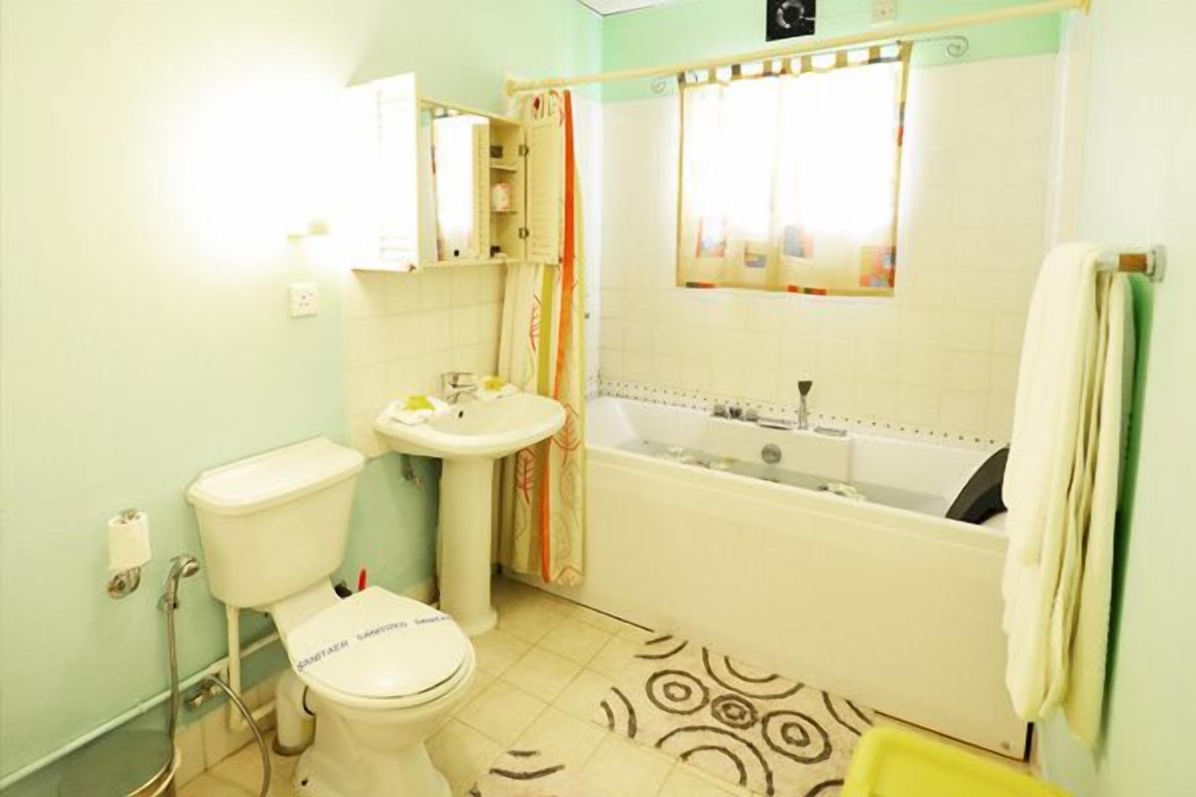Een badkamer met toilet, wastafel, bad en douche.