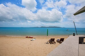 Une plage avec un kayak, des chaises longues et un parasol vert.