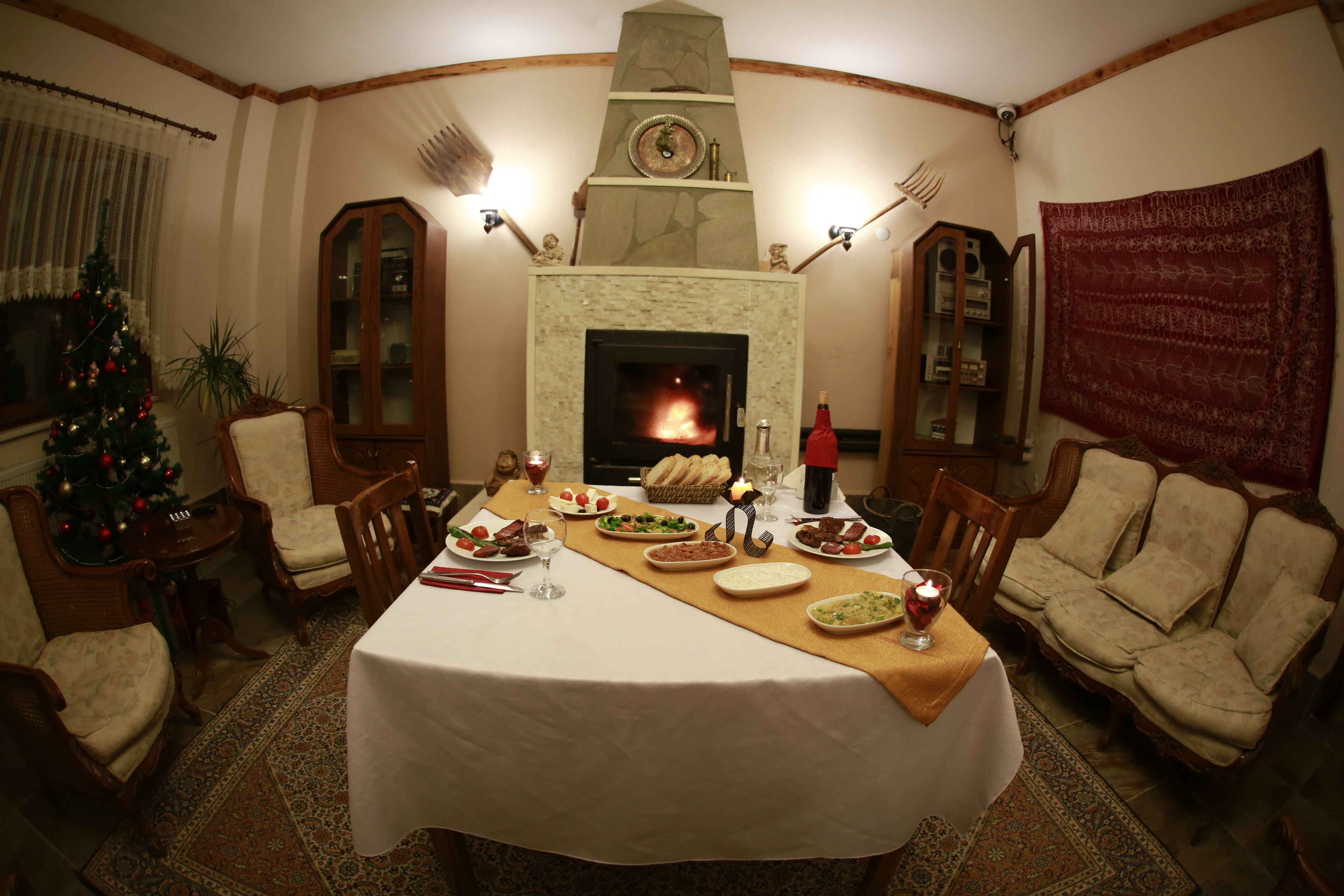 Un comedor con chimenea, un árbol de Navidad y una mesa dispuesta para una comida.