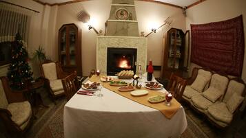 Un comedor con chimenea, un árbol de Navidad y una mesa dispuesta para una comida.