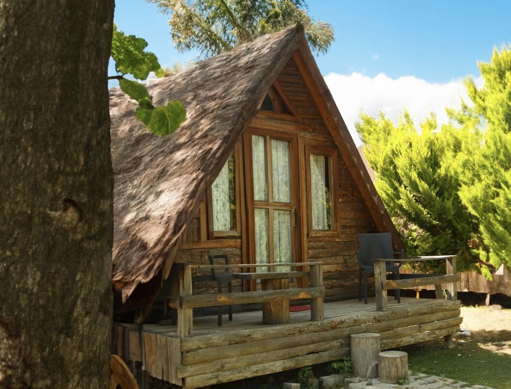 A cabin with a sloped roof, wooden deck, and a bench.