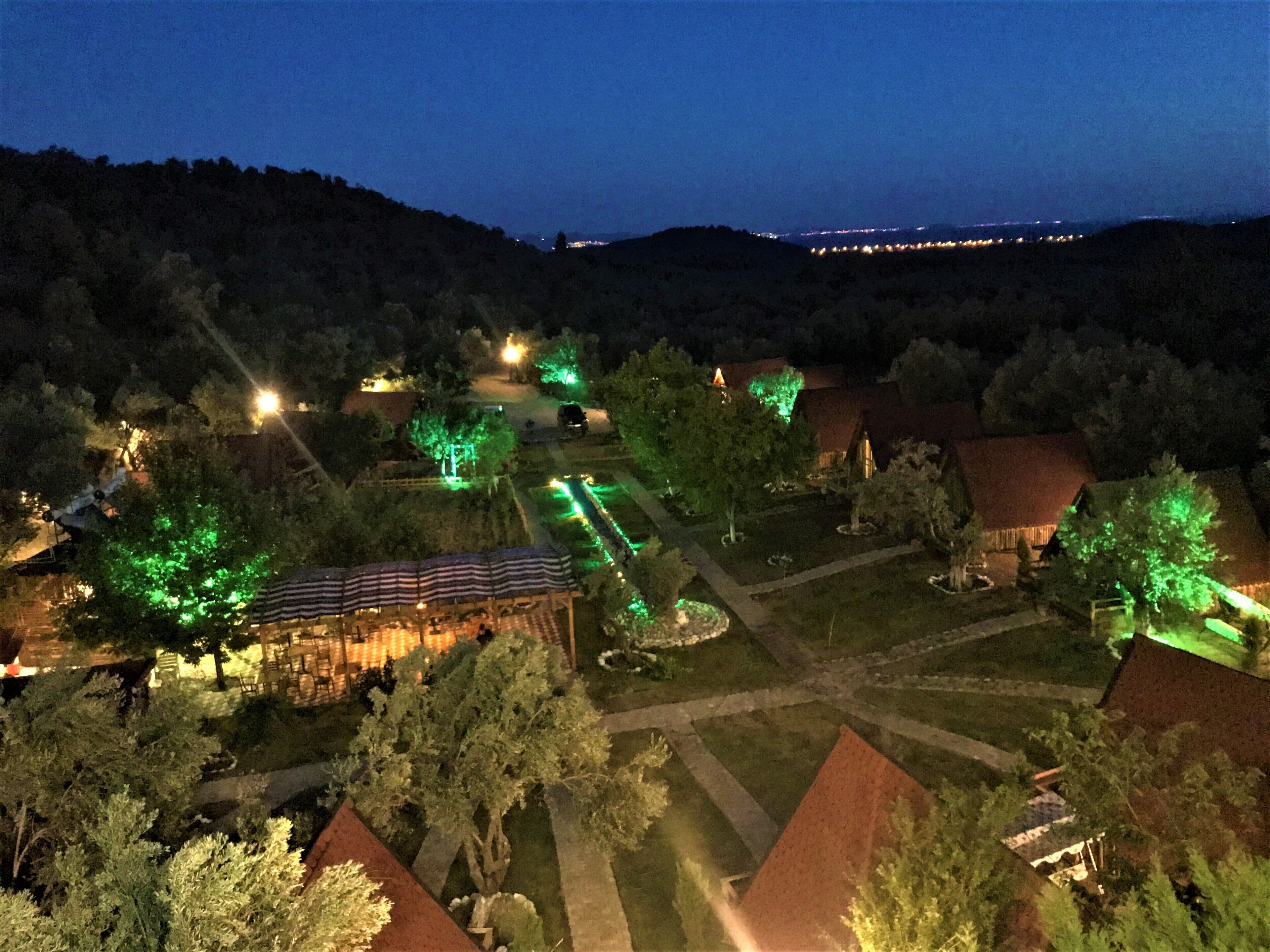 A nighttime view of a rural area with illuminated buildings and pathways.