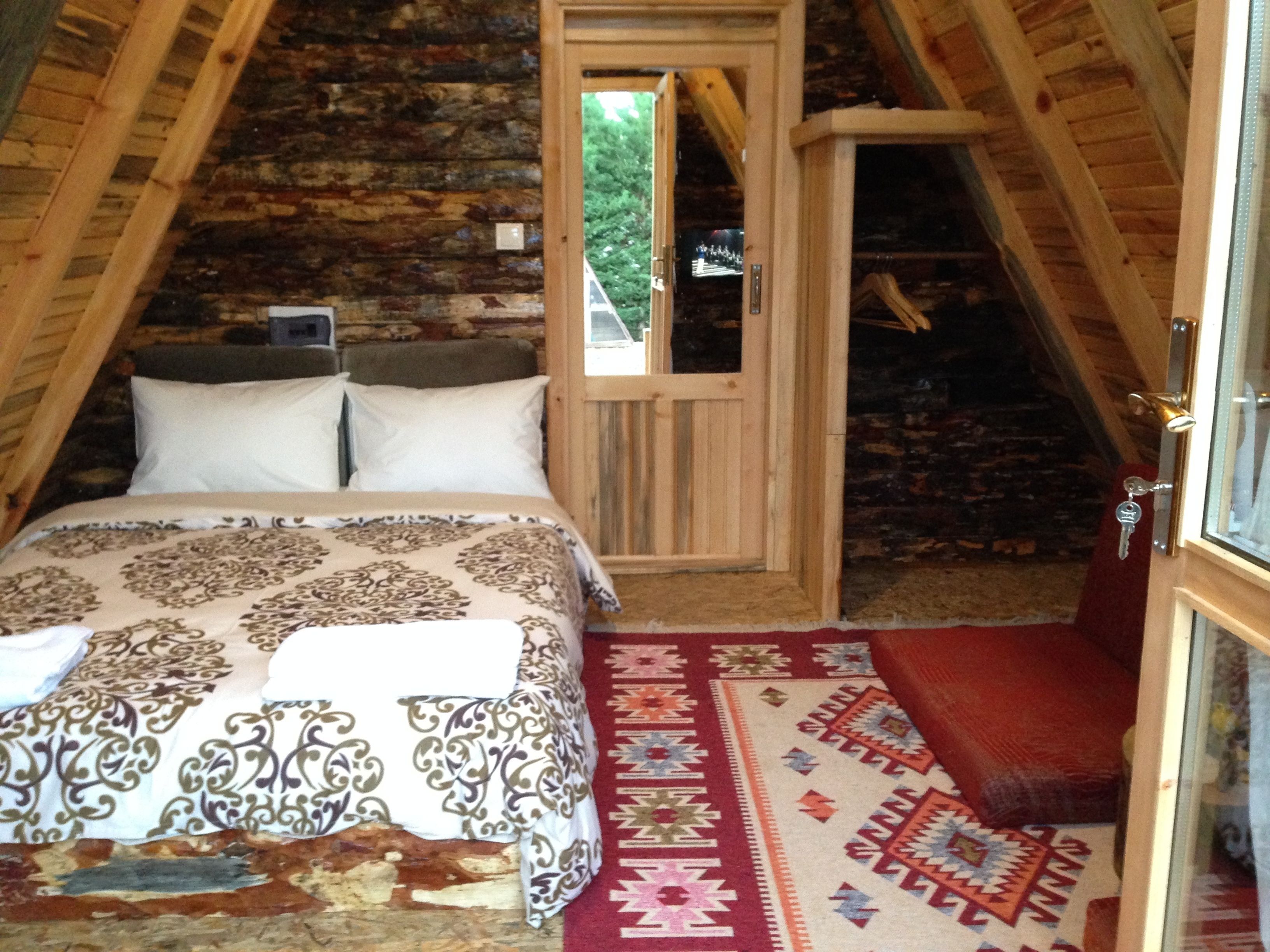 A cozy attic bedroom with a bed, a wooden door, and a view of the outdoors.