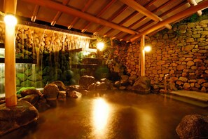 A stone-walled hot spring area with wooden beams and a stone wall.