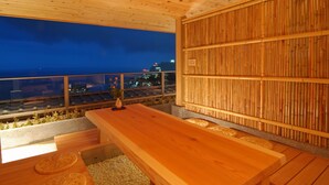 A wooden deck with a long table and benches, overlooking a cityscape at night. - Atami Taikansou (Atami)