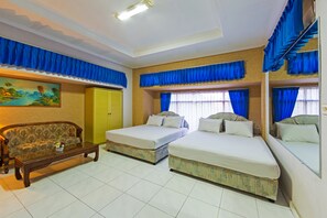 A hotel room with two beds, a sofa, a wooden coffee table, and a painting on the wall.