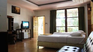 Una habitación de hotel con una cama, televisión, una mesita y un sofá.