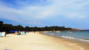 Una playa con sombrillas, barcos y una orilla arenosa.