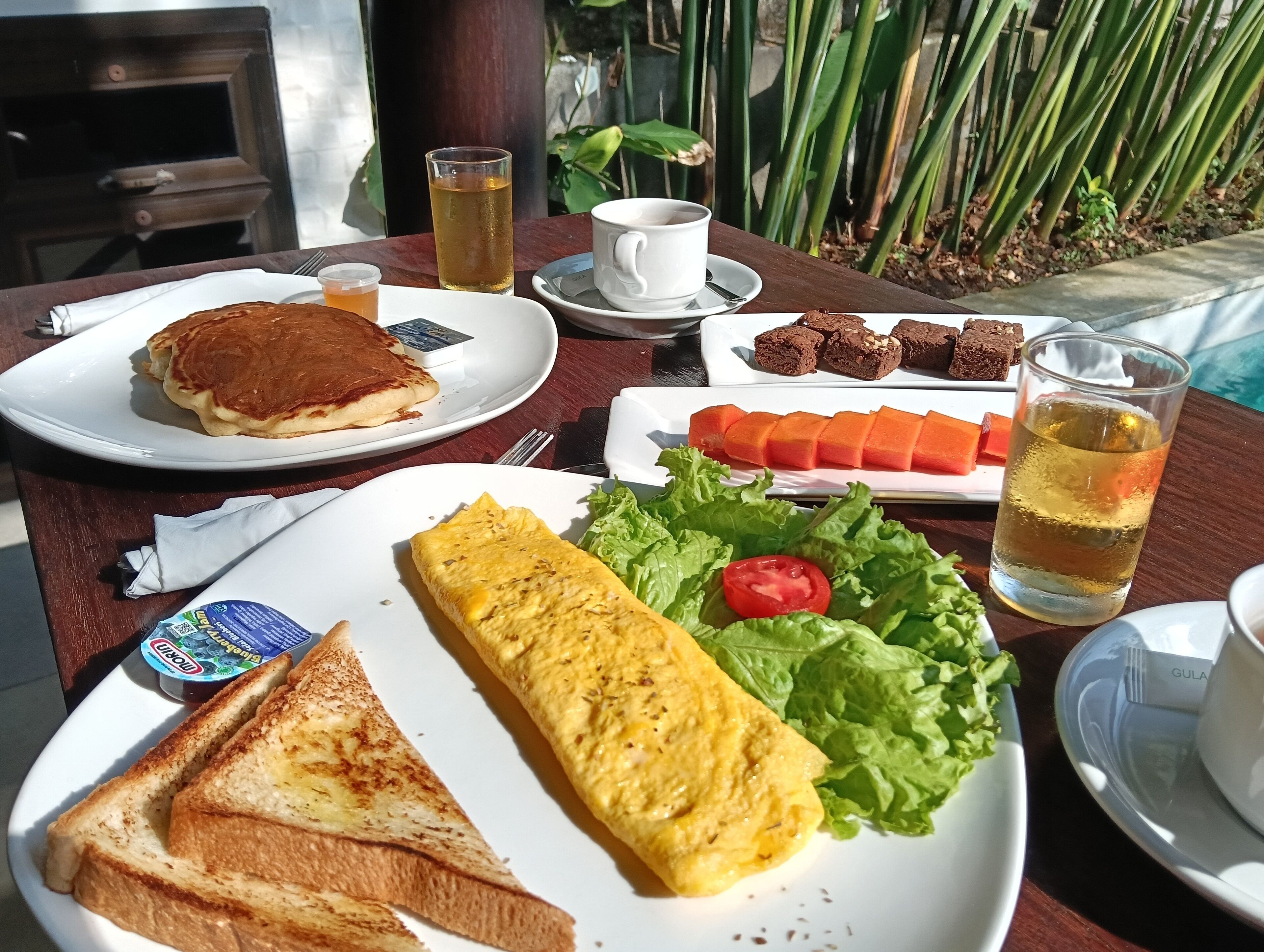 Ein Tisch mit Frühstücksangeboten, darunter Pfannkuchen, Toast, ein Omelett, Karotten und eine Tasse Tee.