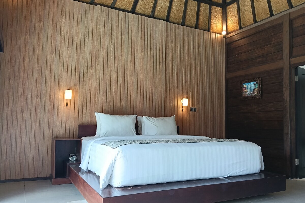 Un dormitorio moderno con un cabecero de listones de madera, una cama con ropa de cama blanca, dos luces de pared y un cuadro pequeño.