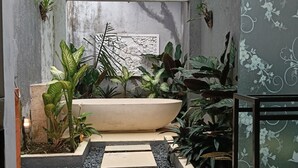Ein kleiner, abgeschlossener Garten mit einem großen Pflanzgefäß, Topfpflanzen und einer Zierwand.