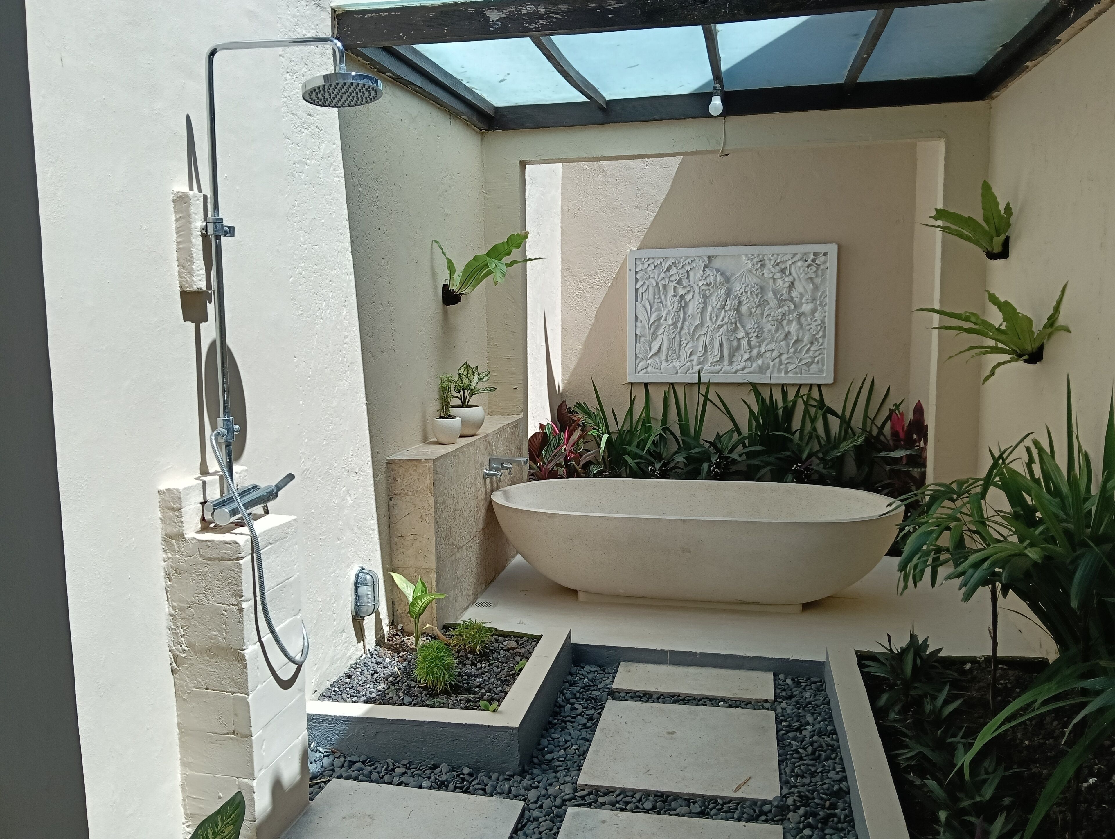 A bathroom with a freestanding bathtub, a shower, and a wall-mounted sink.