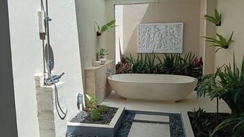A bathroom with a freestanding bathtub, a shower, and a wall-mounted sink.