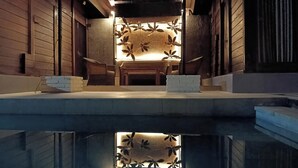 Una piscina con un pontile in legno e un muro decorativo con motivi a foglia.