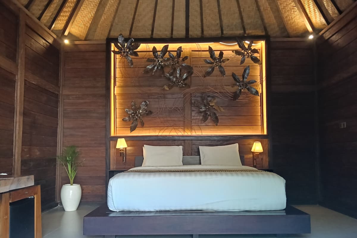 Ein Schlafzimmer mit einem Bett, zwei Nachttischlampen, einer Wandverkleidung und einem Blumentopf.
