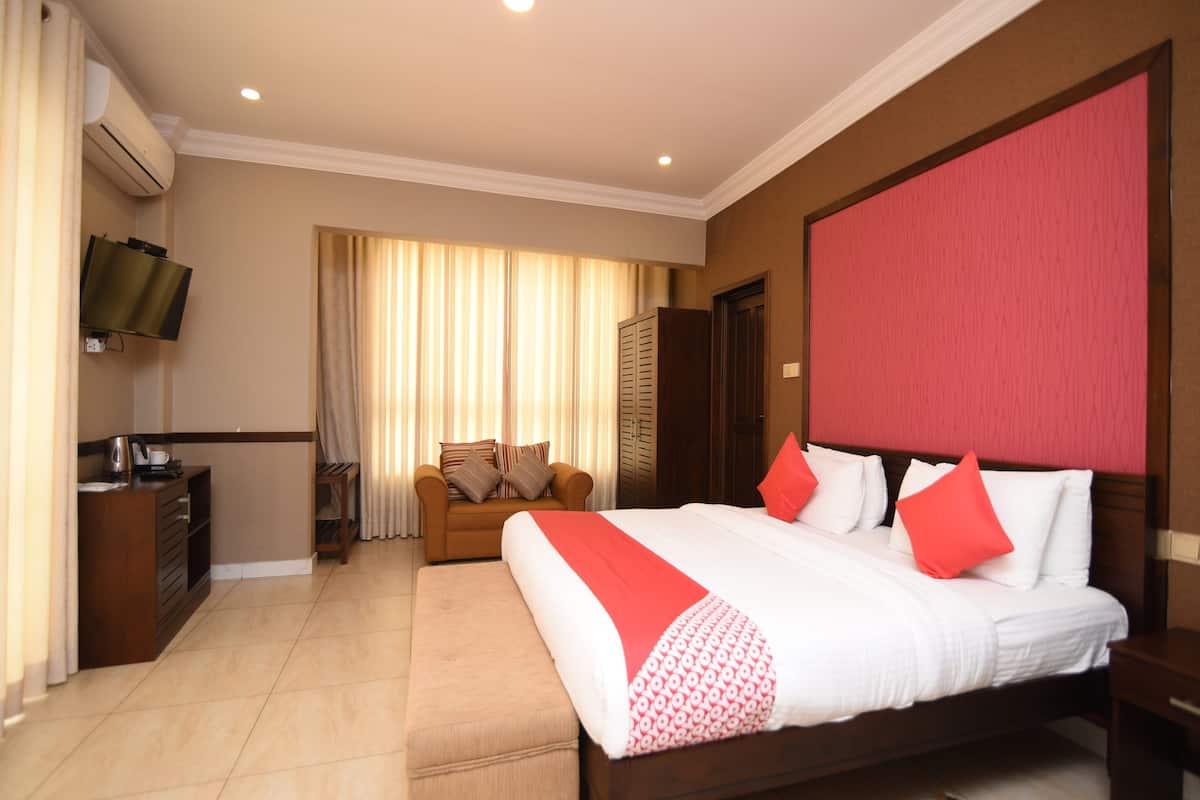 A hotel room with a large bed, a sofa, a TV, and a desk.