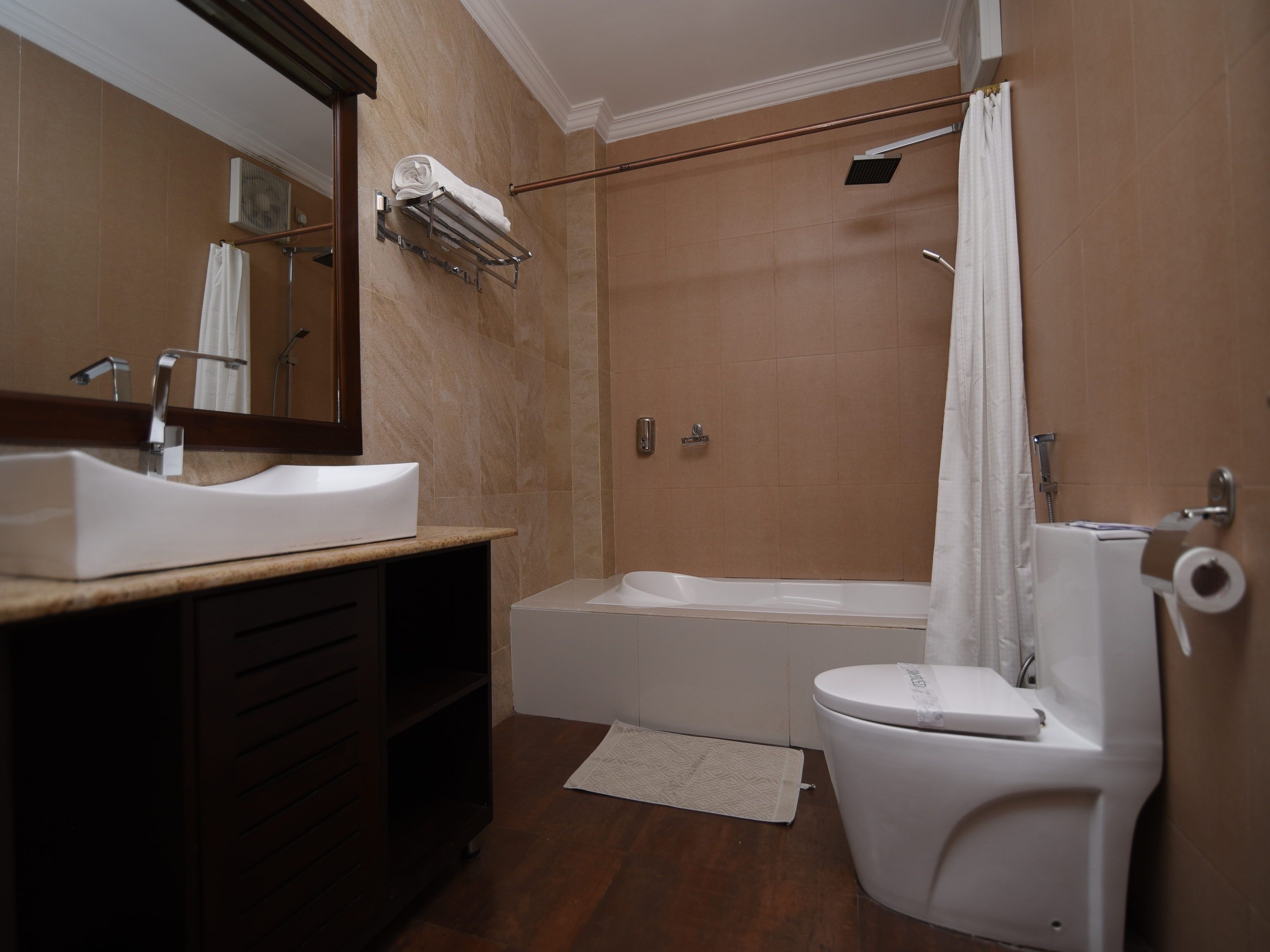 Un baño moderno con lavamanos, espejo, bañera e inodoro.