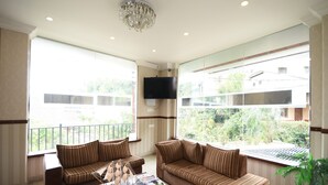 Un salón amplio con ventanas grandes, una araña y un televisor de pantalla plana.