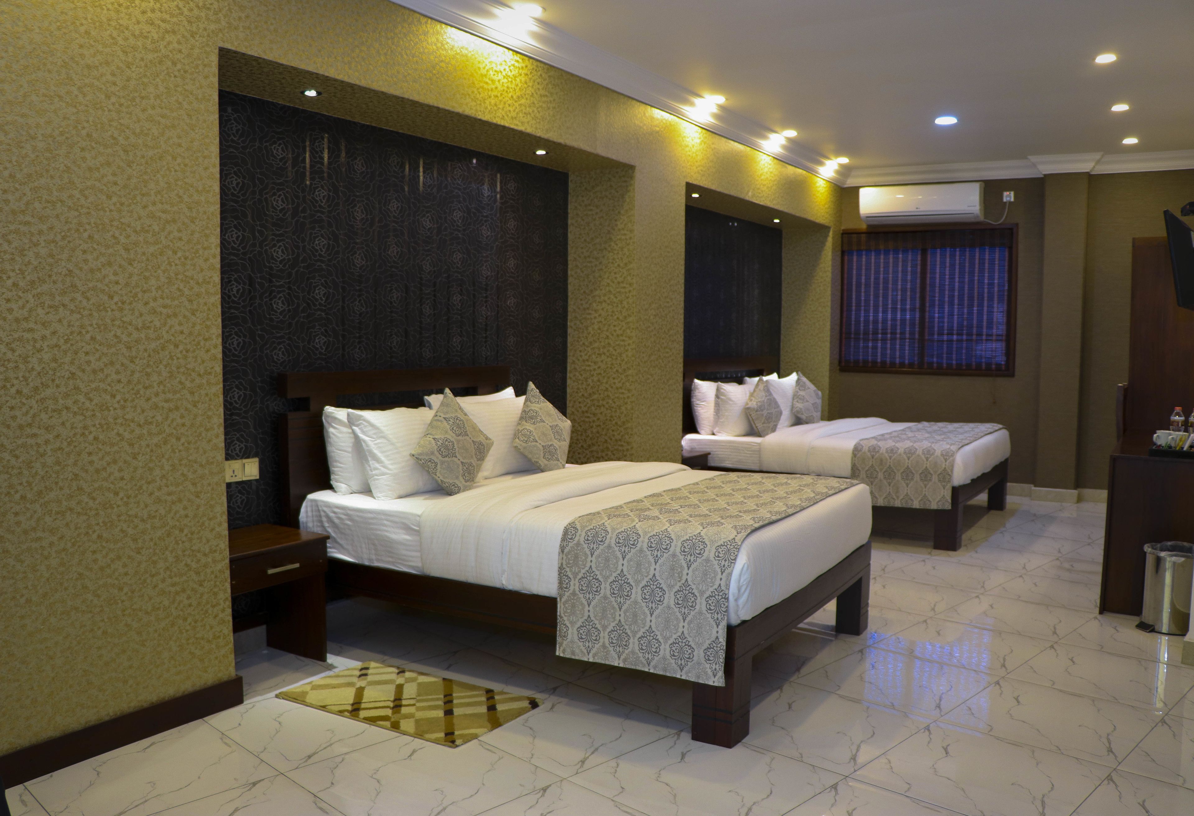 Habitación de hotel con dos camas, un espejo grande y un equipo de aire acondicionado.