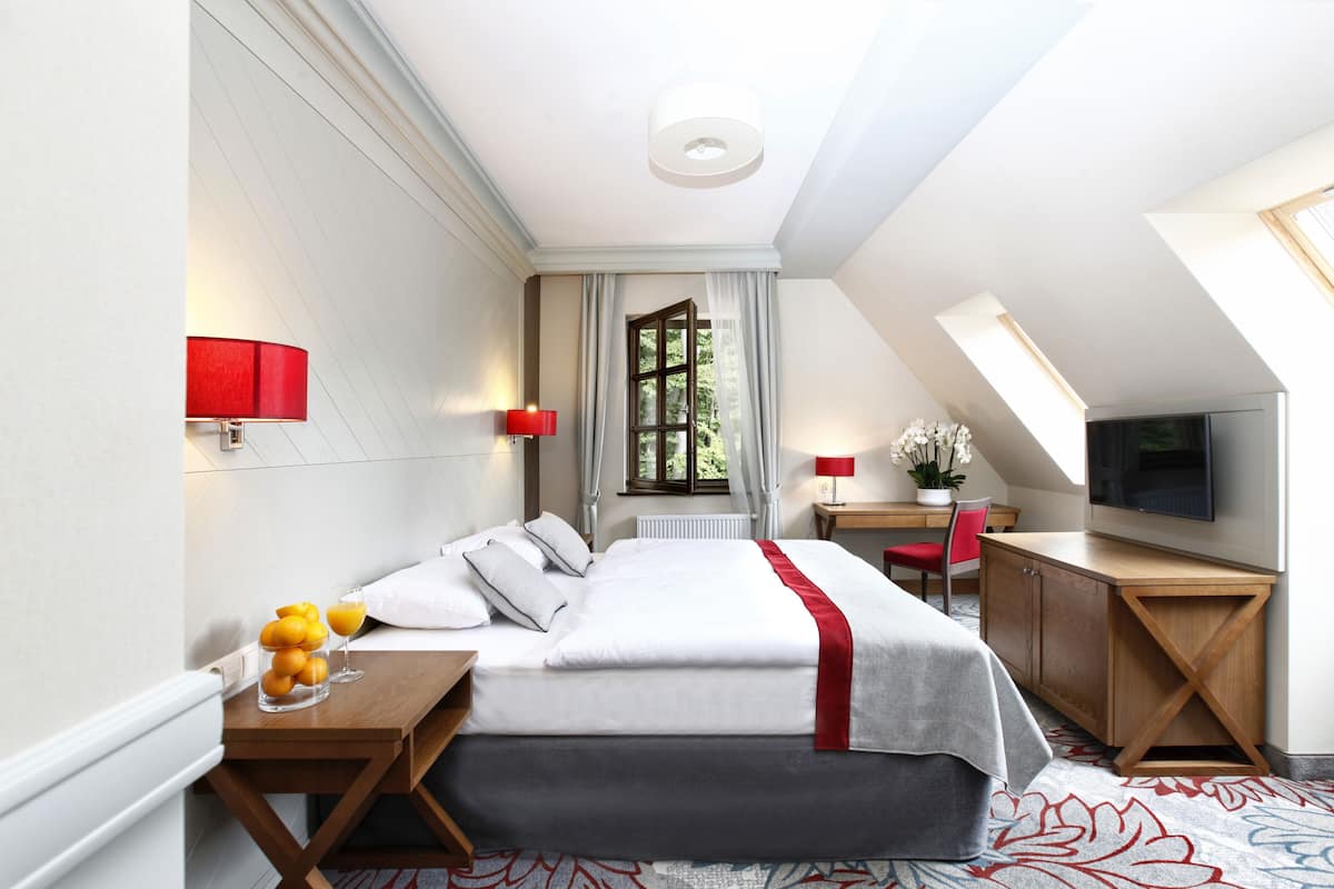 Una habitación de hotel moderna con cama, mesitas de noche, escritorio y televisor.