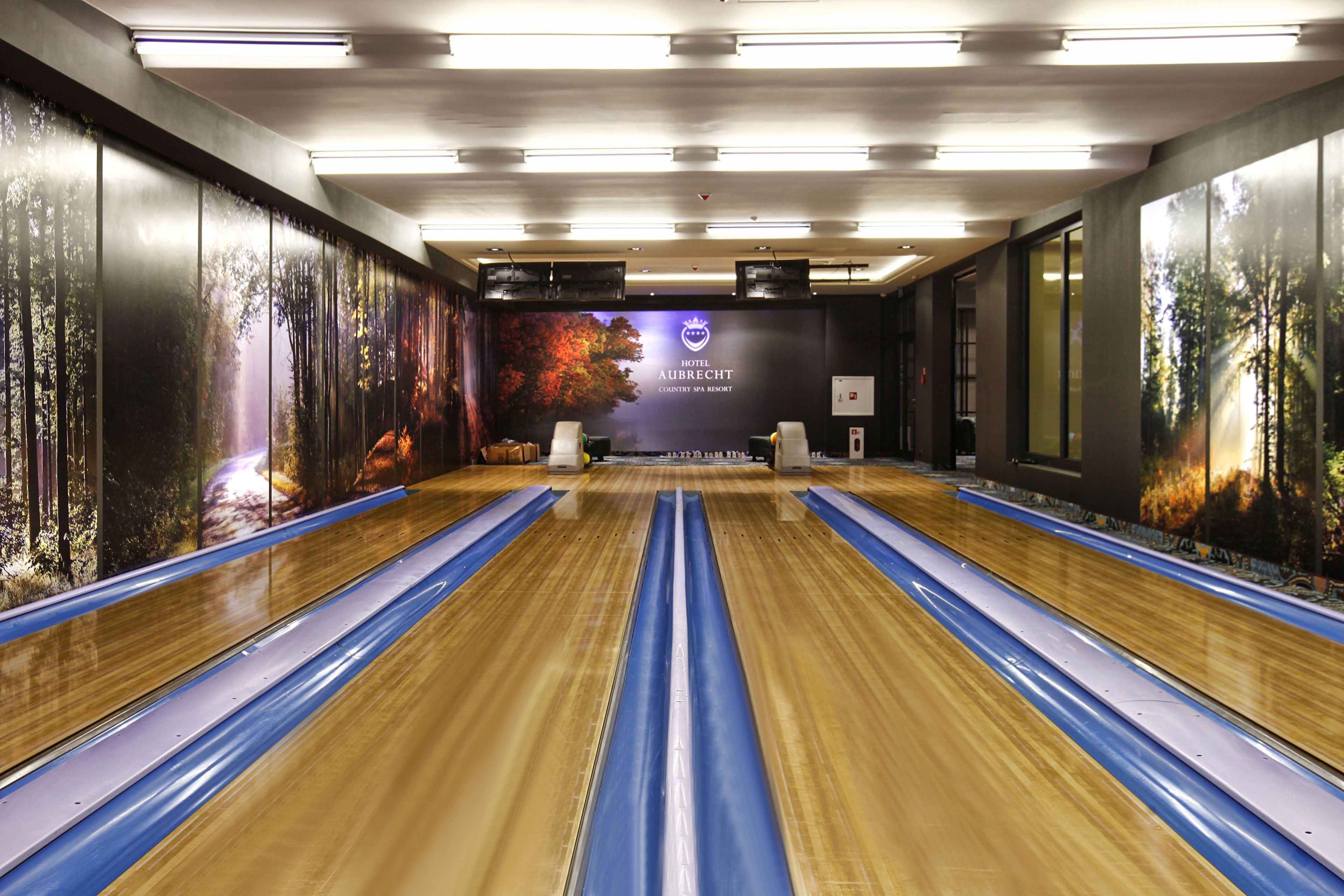 A bowling alley with multiple lanes, a logo on the wall, and a large window on the right.